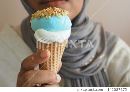 Person holding a blue and white ice cream cone with nuts Person holding a blue and white ice cream cone with nuts 142087875