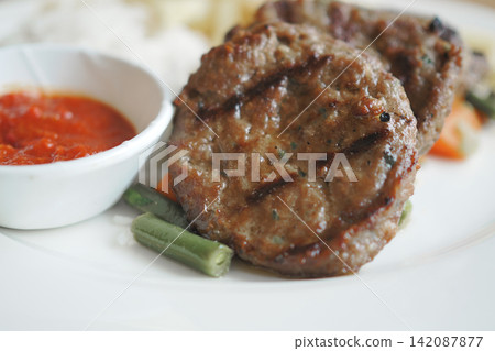 Grilled meat patties served with vegetables and sauce 142087877