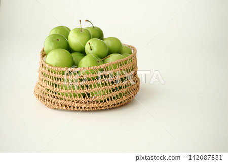 a woven basket filled with fresh, green unripe plums a woven basket filled with fresh, green unripe plums 142087881