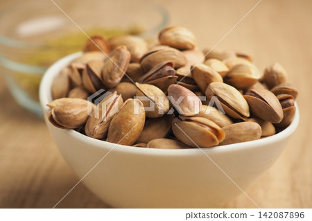 Bowl of pistachio nuts on a wooden table Bowl of pistachio nuts on a wooden table 142087896