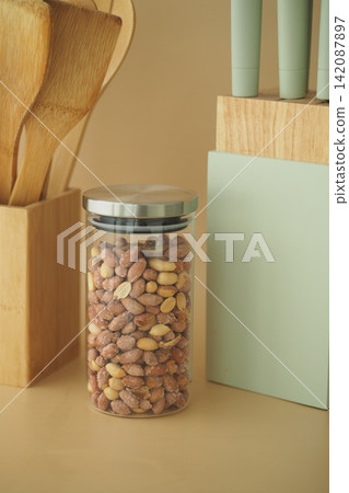 A clear glass jar holds peanuts on a kitchen counter A clear glass jar holds peanuts on a kitchen counter 142087897