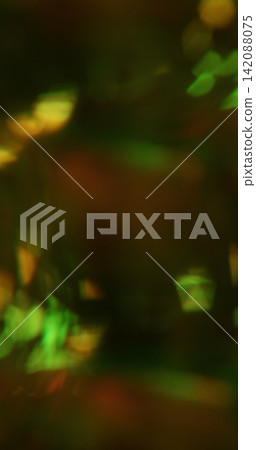 Defocused kaleidoscope. Illuminated light texture. Green yellow orange colorful glisten rainbow reflection on abstract black bokeh art background. Defocused kaleidoscope. Illuminated light texture. Green yellow orange colorful glisten rainbow reflection on abstract black bokeh art background. 142088075