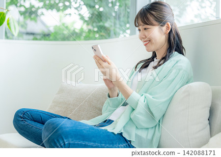使用智能手機的婦女在沙發 142088171