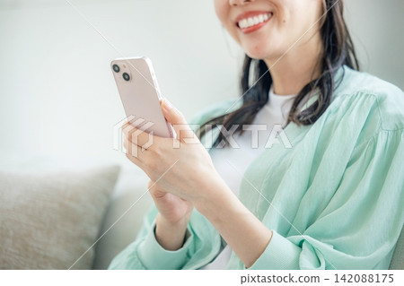 使用智能手機的婦女在沙發 142088175
