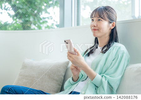 使用智能手機的婦女在沙發 142088176
