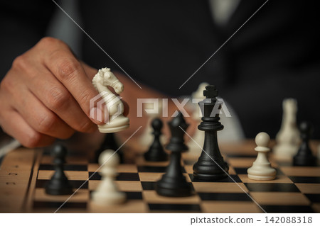 business hand arranging chess knight on wooden board, game strategy 142088318