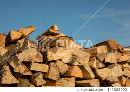 Wood logs are stacked outdoors, showcasing warm tones and textures Wood logs are stacked outdoors, showcasing warm tones and textures 142088900