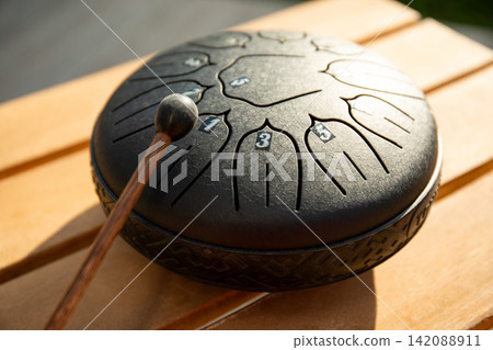 Drum with intricate patterns sits on wooden surface during sunny day Drum with intricate patterns sits on wooden surface during sunny day 142088911
