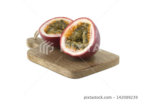 Fresh passion fruit cut in half on a wooden cutting board, showcasing its seeds Fresh passion fruit cut in half on a wooden cutting board, showcasing its seeds 142089239