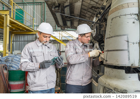 Two mechanics repairing a truck engine in an industrial workshop. Two mechanics repairing a truck engine in an industrial workshop. 142089519
