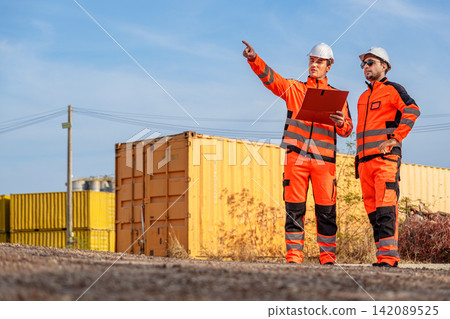 Engineers discussing project progress at construction site for planning. Engineers discussing project progress at construction site for planning. 142089525