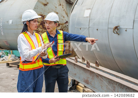 Engineer team collaborating on technical project at industrial site for effective management. 142089682
