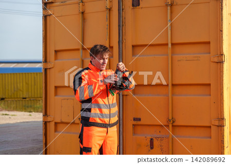Construction worker preparing safety gear outdoors at storage site. Construction worker preparing safety gear outdoors at storage site. 142089692