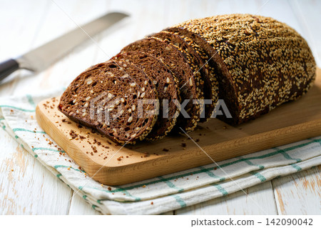 wholemeal rye bread with sesame seeds on white kitchen table, selective focus. wholemeal rye bread with sesame seeds on white kitchen table, selective focus. 142090042