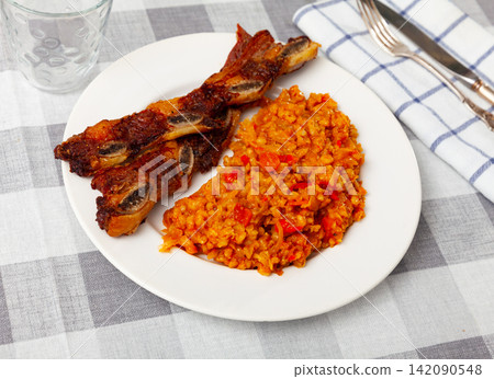 Delicious churrasco style grilled veal ribs served on plate with stewed cabbage with pearl barley porridge. Spain dish Delicious churrasco style grilled veal ribs served on plate with stewed cabbage with pearl barley porridge. Spain dish 142090548