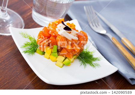 Cube of delicious salmon tartare garnish with avocado on plate at cafe Cube of delicious salmon tartare garnish with avocado on plate at cafe 142090589