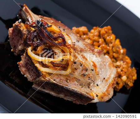 Picture of delicious fried pork with lentils at black plate Picture of delicious fried pork with lentils at black plate 142090591