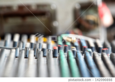 Close up view of an audio mixing console rows of control knobs sliders used for sound recording music production broadcasting live event engineering 142090898