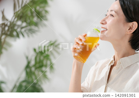 女人從一個塑料瓶喝茶 女人從一個塑料瓶喝茶 142091301