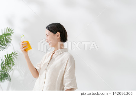 Woman drinking tea from a plastic bottle Woman drinking tea from a plastic bottle 142091305