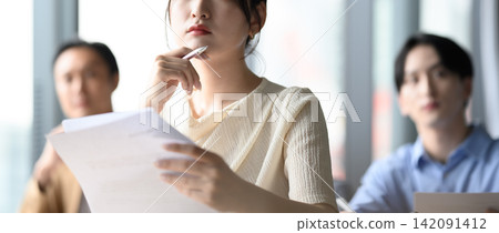 會議期間,一位女士一邊看著文件一邊思考。 會議期間,一位女士一邊看著文件一邊思考。 142091412