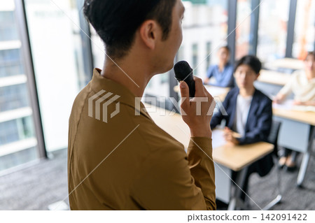 A man giving a lecture with a microphone in his hand. A man giving a lecture with a microphone in his hand. 142091422