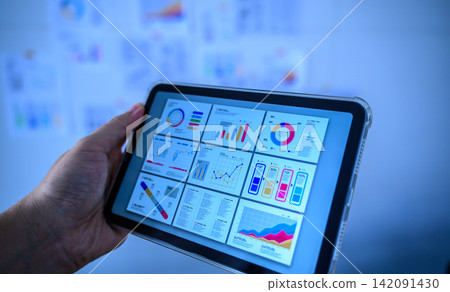 This is a picture of a business person using a tablet to analyze graphs and data. This is a picture of a business person using a tablet to analyze graphs and data. 142091430