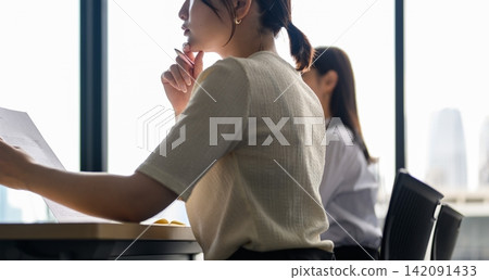 A woman checking documents by the window. A woman checking documents by the window. 142091433