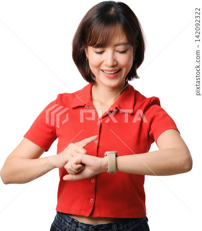 Joyful cheerful Asian woman wearing red shirt pointing finger at smartwatch wrist looking down with happy smiling face expression 142092322
