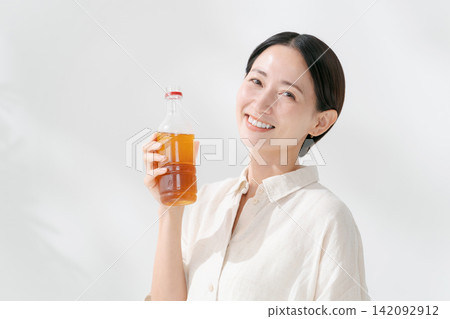 一位微笑的女士正在喝瓶裝茶。 一位微笑的女士正在喝瓶裝茶。 142092912