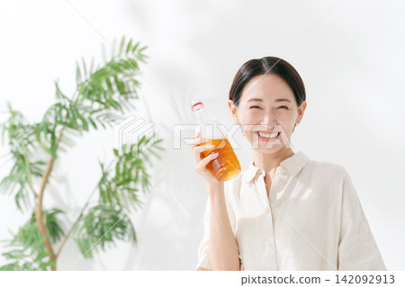 A smiling woman drinking bottled tea. A smiling woman drinking bottled tea. 142092913