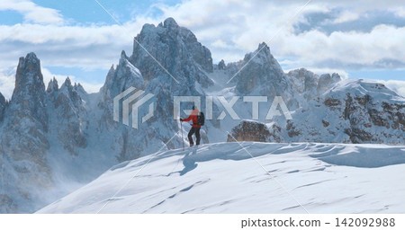 Ski mountaineer standing on a snowy cliff in the Dolomites with majestic alpine peaks in the background, capturing winter adventure, solitude and breathtaking mountain scenery. Ski mountaineer standing on a snowy cliff in the Dolomites with majestic alpine peaks in the background, capturing winter adventure, solitude and breathtaking mountain scenery. 142092988