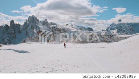 Ski mountaineer crossing a snowy ridge in the Dolomites with dramatic alpine peaks and blue sky in the background, capturing winter adventure and breathtaking mountain landscape. Ski mountaineer crossing a snowy ridge in the Dolomites with dramatic alpine peaks and blue sky in the background, capturing winter adventure and breathtaking mountain landscape. 142092989
