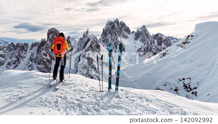 Ski mountaineer crossing a snowy ridge in the Dolomites with dramatic alpine peaks and blue sky in the background, capturing winter adventure and breathtaking mountain landscape. Ski mountaineer crossing a snowy ridge in the Dolomites with dramatic alpine peaks and blue sky in the background, capturing winter adventure and breathtaking mountain landscape. 142092992