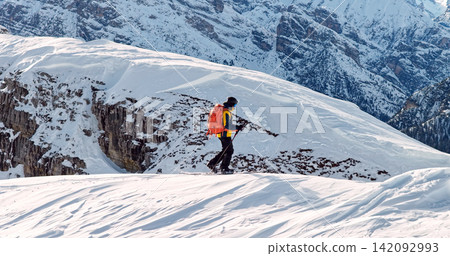 Ski mountaineer crossing a snowy ridge in the Dolomites with dramatic alpine peaks and blue sky in the background, capturing winter adventure and breathtaking mountain landscape. Ski mountaineer crossing a snowy ridge in the Dolomites with dramatic alpine peaks and blue sky in the background, capturing winter adventure and breathtaking mountain landscape. 142092993