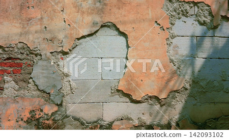 Weathered wall with peeling plaster and exposed concrete blocks. Weathered wall with peeling plaster and exposed concrete blocks. 142093102