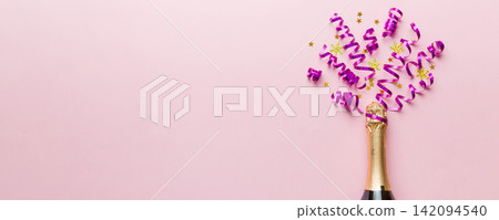 Creative flat lay composition with bottle of champagne and space for text on color background. Champagne bottle with colorful party streamers. holiday or christmas concept Creative flat lay composition with bottle of champagne and space for text on color background. Champagne bottle with colorful party streamers. holiday or christmas concept 142094540