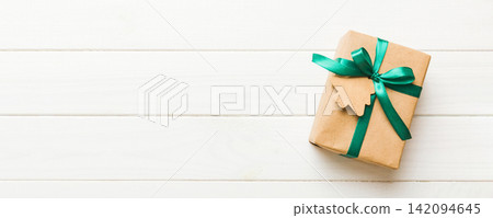 wrapped christmas or other holiday handmade present in paper with colored ribbon. Present box, decoration of gift on colourfull table, top view with copy space wrapped christmas or other holiday handmade present in paper with colored ribbon. Present box, decoration of gift on colourfull table, top view with copy space 142094645