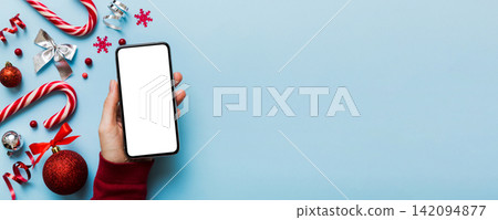 christmas mockup with space for text. christmas advertising, app template. hand holding phone with empty screen on table background. Happy New Year and Xmas Flat lay christmas mockup with space for text. christmas advertising, app template. hand holding phone with empty screen on table background. Happy New Year and Xmas Flat lay 142094877
