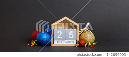 25 december. Christmas composition on colored background with a wooden calendar, with a gift box, toys, bauble copy space 25 december. Christmas composition on colored background with a wooden calendar, with a gift box, toys, bauble copy space 142094903