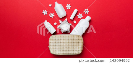 Christmas flat lay with makeup cosmetic products in cosmetic bag on colored background. Top view New year Beauty concept Christmas flat lay with makeup cosmetic products in cosmetic bag on colored background. Top view New year Beauty concept 142094992