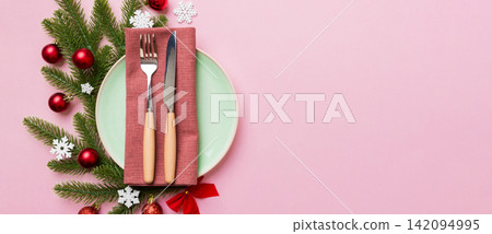 Christmas table place setting with christmas decor and plates, kine, fork and spoon. Christmas holiday background. Top view with copy space Christmas table place setting with christmas decor and plates, kine, fork and spoon. Christmas holiday background. Top view with copy space 142094995