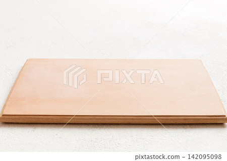 Perspective view of wooden cutting board on cement background. Empty space for your design Perspective view of wooden cutting board on cement background. Empty space for your design 142095098