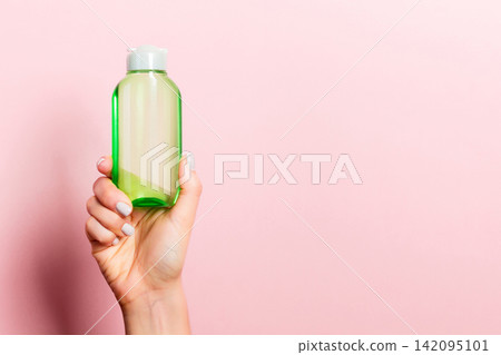 Female hand holding cream bottle of lotion isolated. Girl give tube cosmetic products on pink background Female hand holding cream bottle of lotion isolated. Girl give tube cosmetic products on pink background 142095101