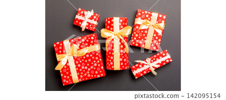 Gift box with gold bow for Christmas or New Year day on black background, top view Gift box with gold bow for Christmas or New Year day on black background, top view 142095154