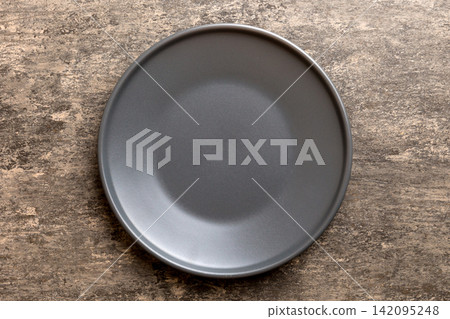 Top view of black plate on cement background. Empty space for your design Top view of black plate on cement background. Empty space for your design 142095248
