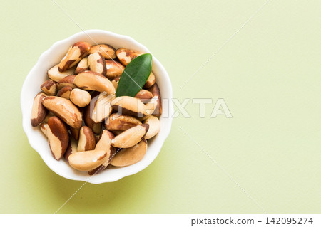 Fresh healthy Brazil nuts in bowl on colored table background. Top view Healthy eating bertholletia concept. Super foods Fresh healthy Brazil nuts in bowl on colored table background. Top view Healthy eating bertholletia concept. Super foods 142095274