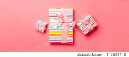Gift box with pink bow for Christmas or New Year day on living coral background, top view 142095348