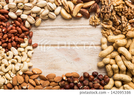 different nuts frame background. Close up, top view, flat lay with vopy space. Walnut, pistachios, almonds, hazelnuts and cashews different nuts frame background. Close up, top view, flat lay with vopy space. Walnut, pistachios, almonds, hazelnuts and cashews 142095386