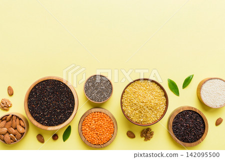 Various superfoods in smal bowl on colored background. Superfood as rice, chia, quinoa, lentils, nuts, sesame seeds, almonds. top view copy space Various superfoods in smal bowl on colored background. Superfood as rice, chia, quinoa, lentils, nuts, sesame seeds, almonds. top view copy space 142095500
